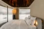 Dormitorio con fachada de vidrio y cortinas automatizadas.